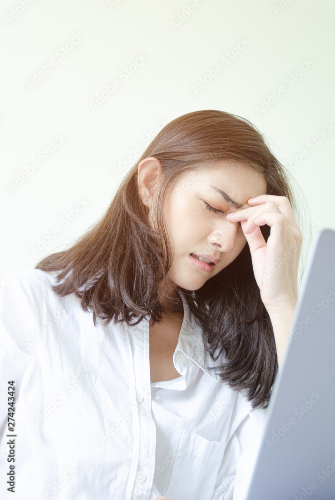 Women have headaches. And stressed from work.In the white room there is a lady inside.Do not focus on the main object of this image. Women have headaches. And stressed from work.In the white room there is a lady inside.Do not focus on the main object of this image.