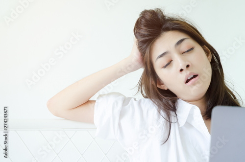 Asian women sitting at home on the couch She is very tired and sleepy.Do not focus on the main object of this image.