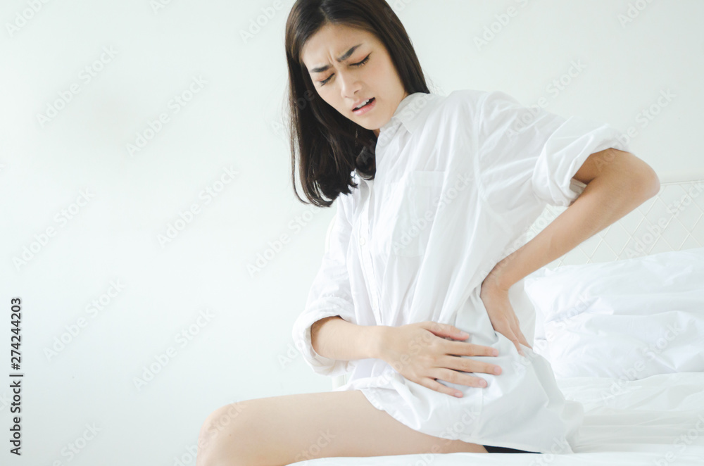 Women wear white shirts and pink pants on the bed in a room with hip pain in the morning.Asian women Have back pain In the morning.Back pain is caused by a mattress.Do not focus on objects. Women wear white shirts and pink pants on the bed in a room with hip pain in the morning.Asian women Have back pain In the morning.Back pain is caused by a mattress.Do not focus on objects.