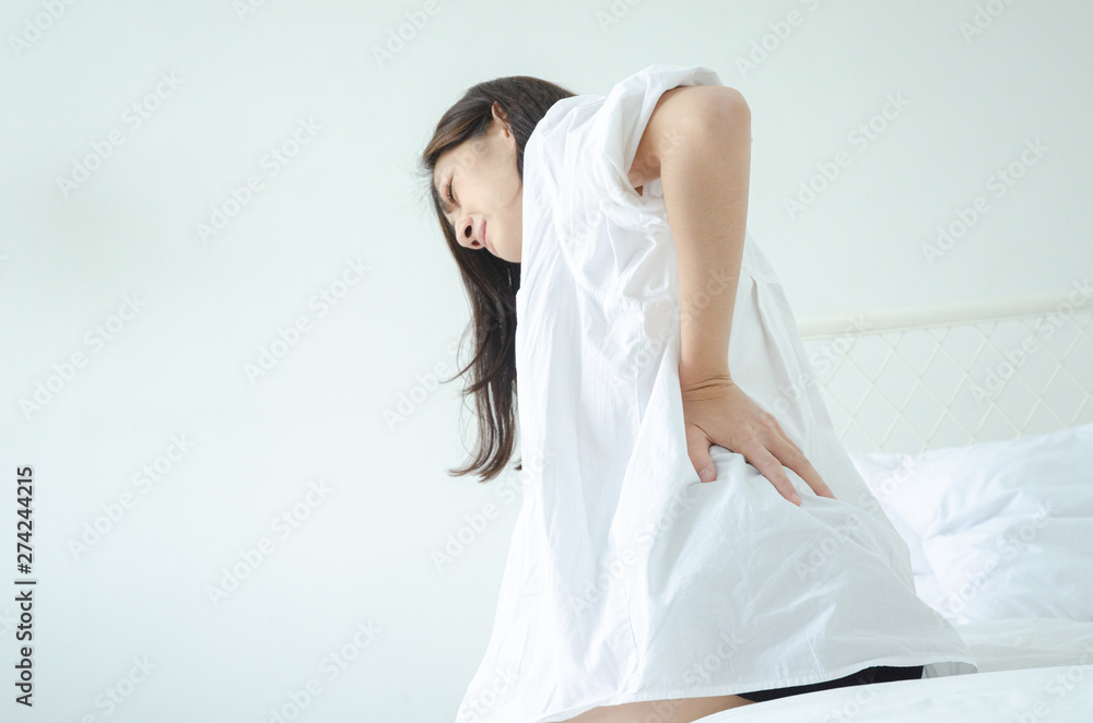Women wear white shirts and pink pants on the bed in a room with hip pain in the morning.Asian women Have back pain In the morning.Back pain is caused by a mattress.Do not focus on objects. Women wear white shirts and pink pants on the bed in a room with hip pain in the morning.Asian women Have back pain In the morning.Back pain is caused by a mattress.Do not focus on objects.