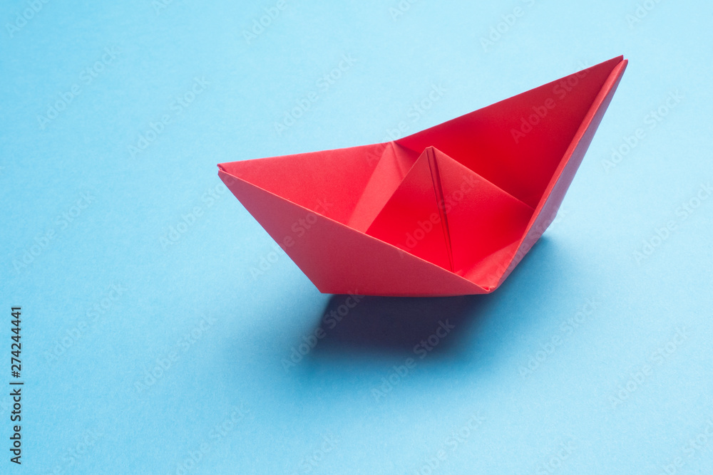 Red origami boat on blue background. Red paper ship on blue. Red origami boat on blue background. Red paper ship on blue.