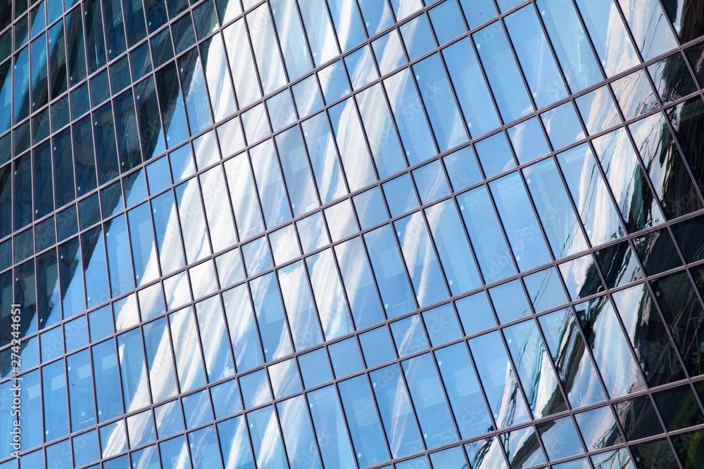 Glass mirror skyscraper wall with blue sky and white clouds reflection close up, modern business center view, financial city district, commercial downtown design, geometric texture pattern, copy space Glass mirror skyscraper wall with blue sky and white clouds reflection close up, modern business center view, financial city district, commercial downtown design, geometric texture pattern, copy space