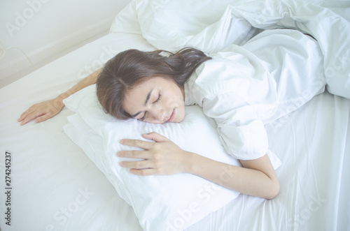 Beautiful woman sleeping in the bedroom. Woman lying face down on the bed.Girl wearing a pajama sleep on a bed in a white room in the morning.Warm tone.