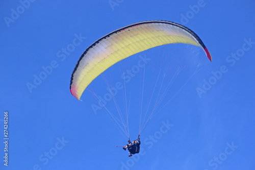 Tandem paraglider flying yellow wing