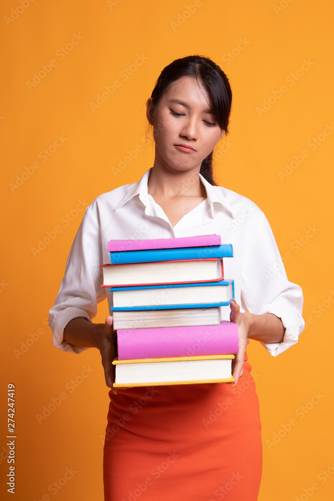 Unhappy young Asian woman studying with may books. Unhappy young Asian woman studying with may books.