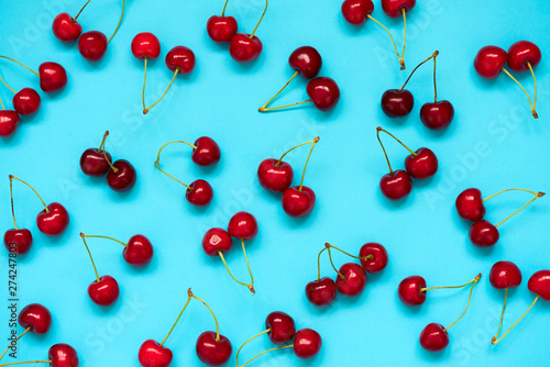 Red ripe cherry beries on blue background. Cherry pattern. Flat lay. Healthy food concept.