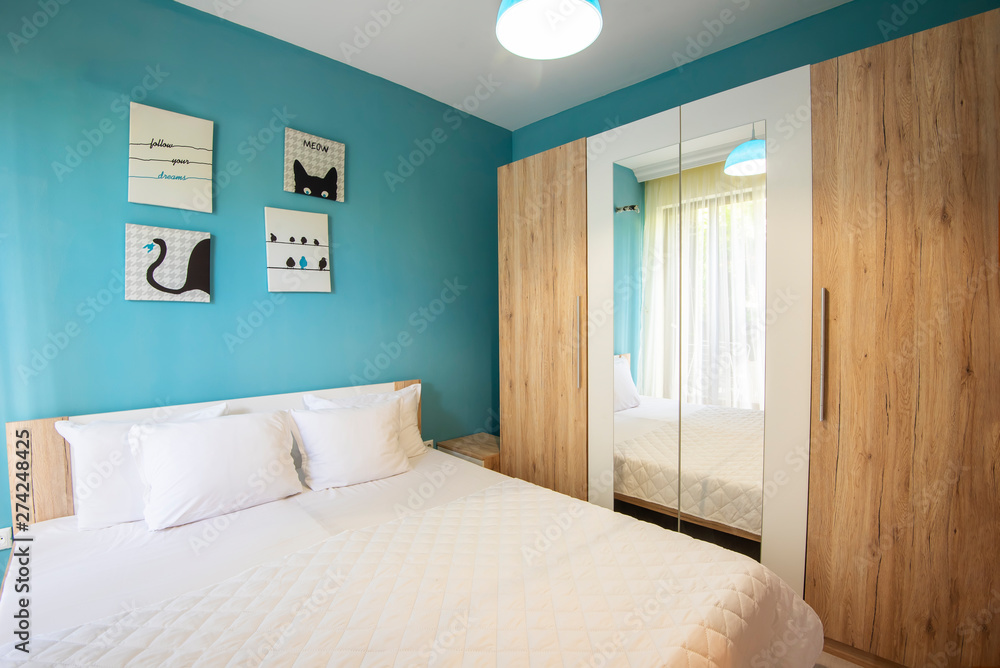 Hotel bedroom with blue walls, white curtains, pillowcases and sheets. Hotel bedroom with blue walls, white curtains, pillowcases and sheets.