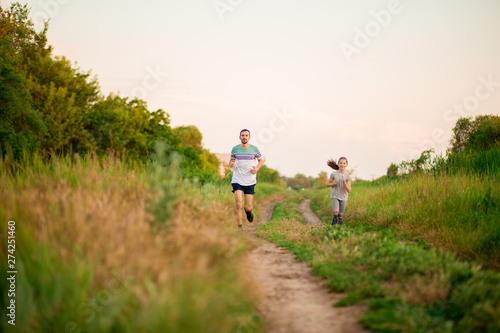 Father and daughter jogging. Cheerful father and daughter run in park together. Sport life concept