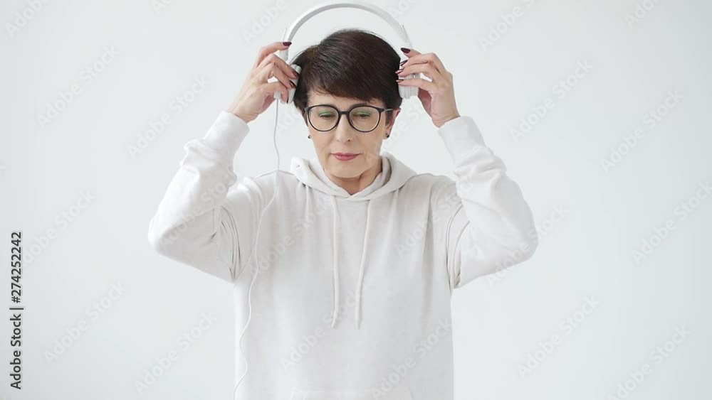 Love for music concept. Mature Woman Streams Music in Headphones on a white background Love for music concept. Mature Woman Streams Music in Headphones on a white background