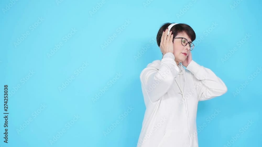 Love for music concept. Mature Woman Streams Music in Headphones on a blue background Love for music concept. Mature Woman Streams Music in Headphones on a blue background