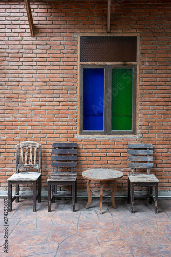 Antique set of wooden table and chairs with classic color glass window on the old brick wall interior vintage style