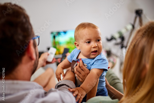 Young parents watching TV with baby boy.