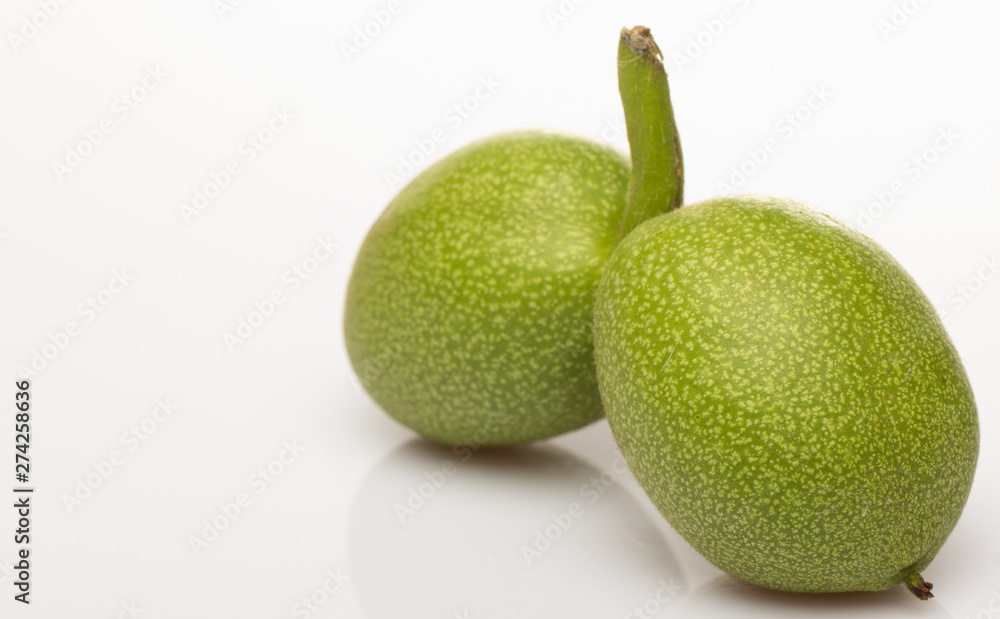 Two green walnut on a white background close-up Two green walnut on a white background close-up