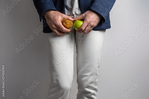 A man at the level of the genitals , holding a ripe and rotten apple. Disease for men. The concept of protection of sexually transmitted infections photo