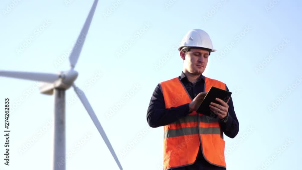Engineer of Caucasian appearance examines the work of a windmill on tablet Engineer of Caucasian appearance examines the work of a windmill on tablet