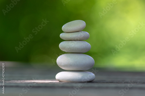 Harmony and balance  cairns  simple poise pebbles on wooden table  natural green background  simplicity rock zen sculpture