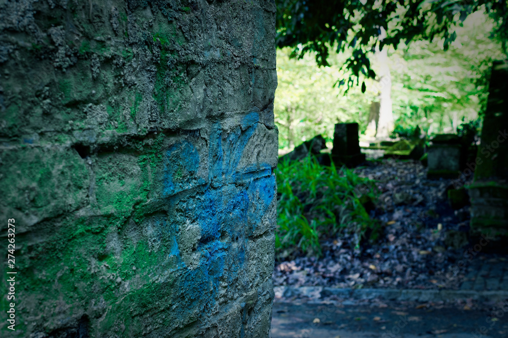 Kaputter Grabstein mit Beschädigungen auf einem Friedhof in grün Kaputter Grabstein mit Beschädigungen auf einem Friedhof in grün