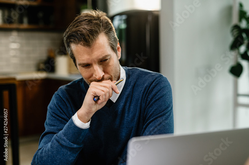 Pensive businessman using laptop while working at home.