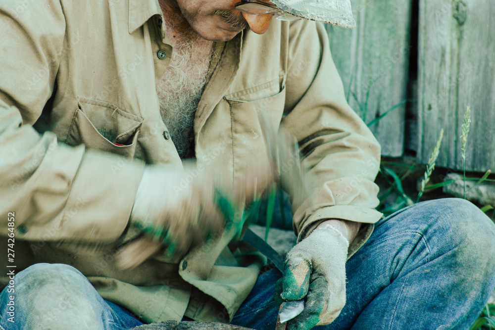 Fototapeta premium traditional iron forging, artisan sharpens a sharp knife blade with a hammer.