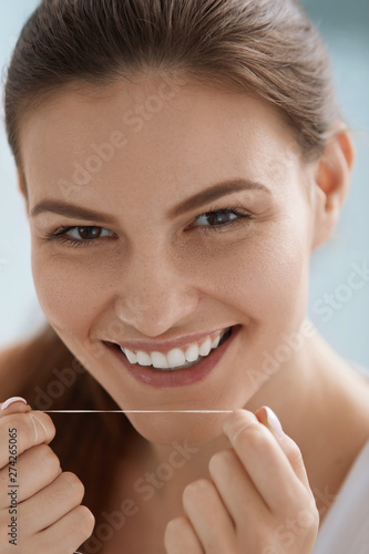 Dental floss. Smiling woman cleaning white teeth with floss