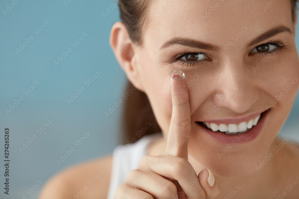 Eye care. Smiling woman with contact eye lens on finger closeup Eye care. Smiling woman with contact eye lens on finger closeup