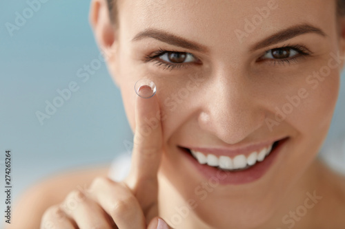 Eye care. Smiling woman with contact eye lens on finger closeup