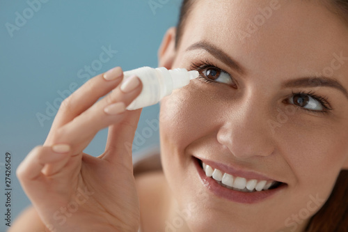 Eye drop. Woman applying lubricant eye drops in her eyes closeup