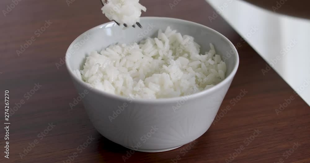 Closeup of woman eating rice from bowl with fork Closeup of woman eating rice from bowl with fork