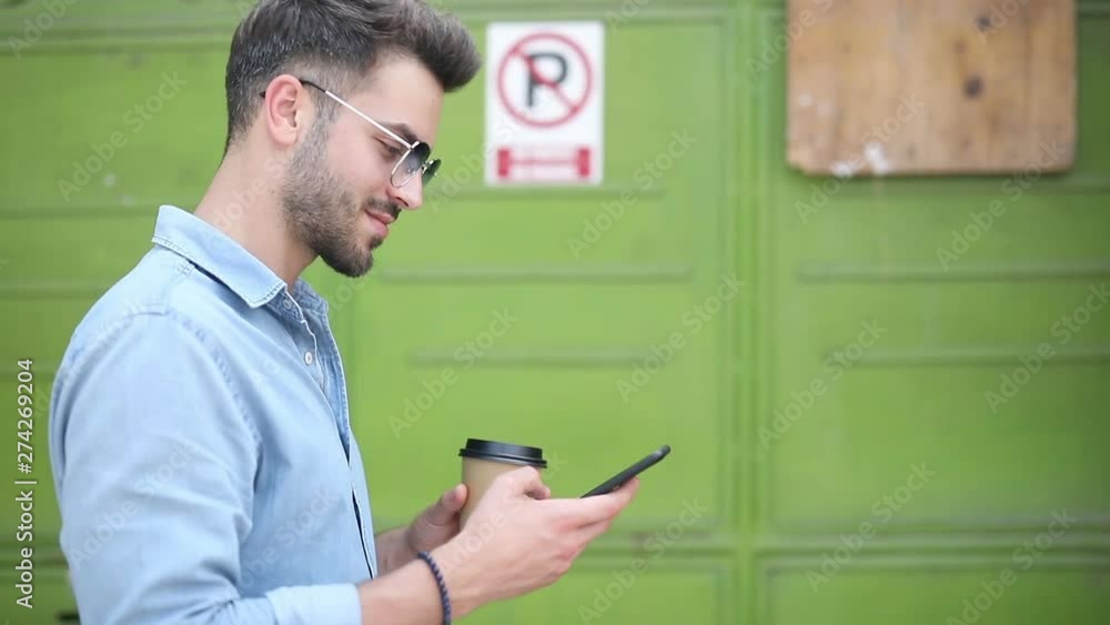 side view of man walking, texting and drinking coffee side view of man walking, texting and drinking coffee
