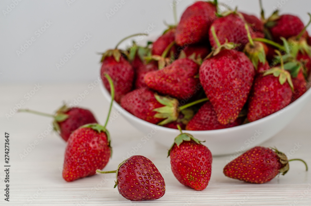 Fresh summer ripe strawberries in a white plate on a white wooden background Fresh summer ripe strawberries in a white plate on a white wooden background