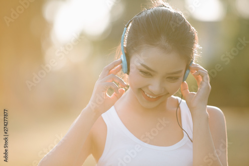 Beautiful Young Woman with Headphones Outdoors. Enjoying Music