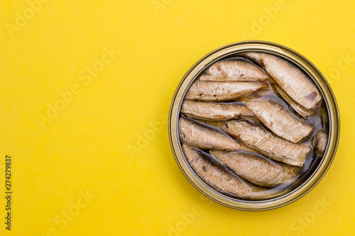 Open canned box with sprats from top to yellow background with free space for text