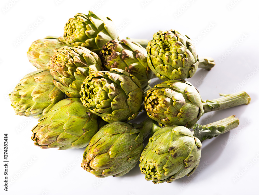 Fototapeta premium Uncooked green artichokes on a white surface