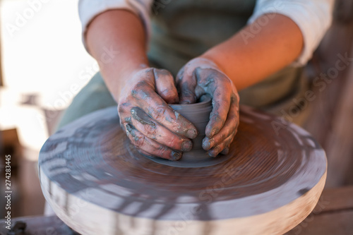 Potter is creating earthenware on potter's wheel.