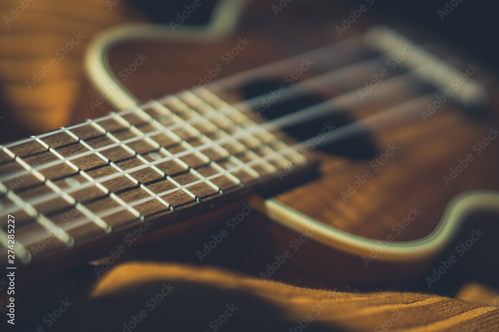Ukulele closeup. Orange and dark background. Ukulele closeup. Orange and dark background.