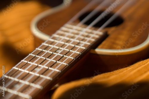 Ukulele closeup. Orange and dark background.