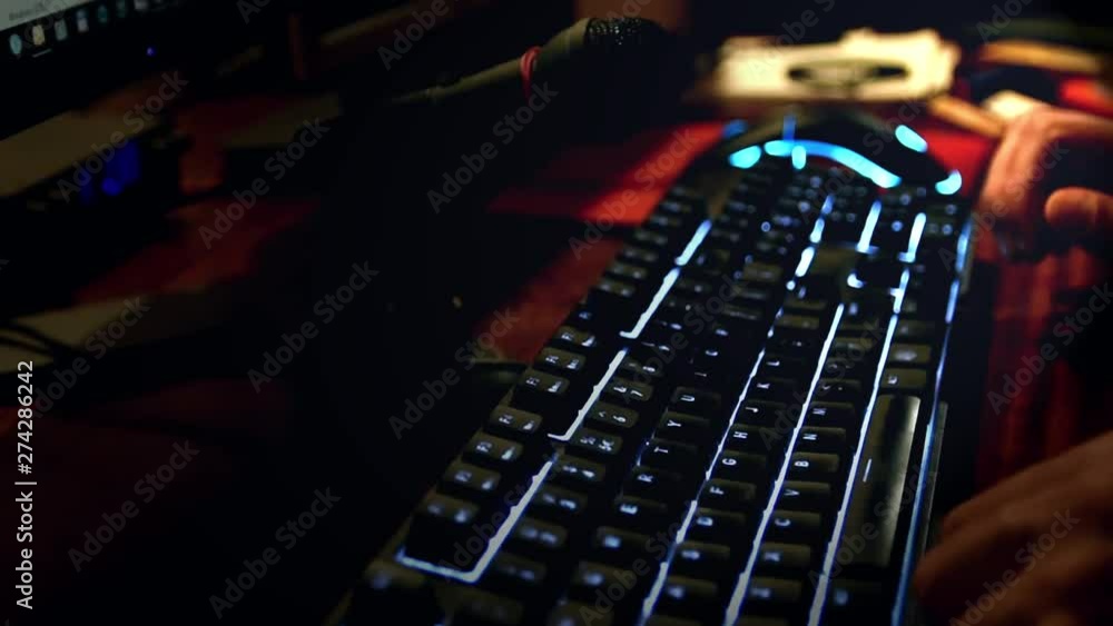 man speaking to a microphone while he is typing in an illuminated keyboard man speaking to a microphone while he is typing in an illuminated keyboard
