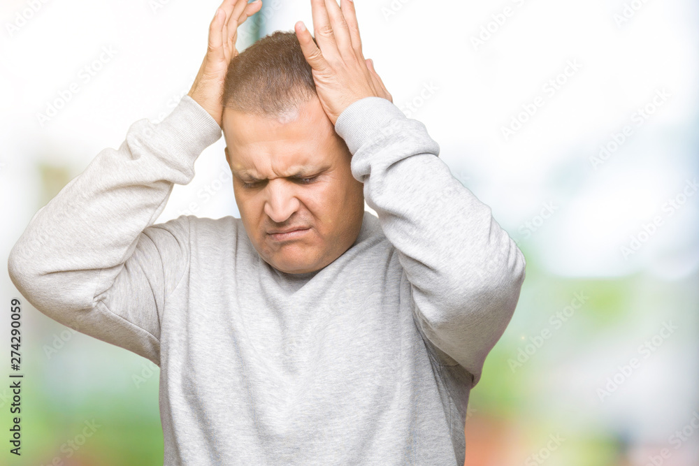 Middle age arab man wearing sport sweatshirt over isolated background suffering from headache desperate and stressed because pain and migraine. Hands on head. Middle age arab man wearing sport sweatshirt over isolated background suffering from headache desperate and stressed because pain and migraine. Hands on head.