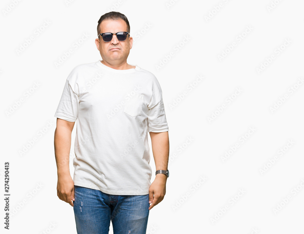 Middle age arab man wearig white t-shirt and sunglasses over isolated background with serious expression on face. Simple and natural looking at the camera. Middle age arab man wearig white t-shirt and sunglasses over isolated background with serious expression on face. Simple and natural looking at the camera.