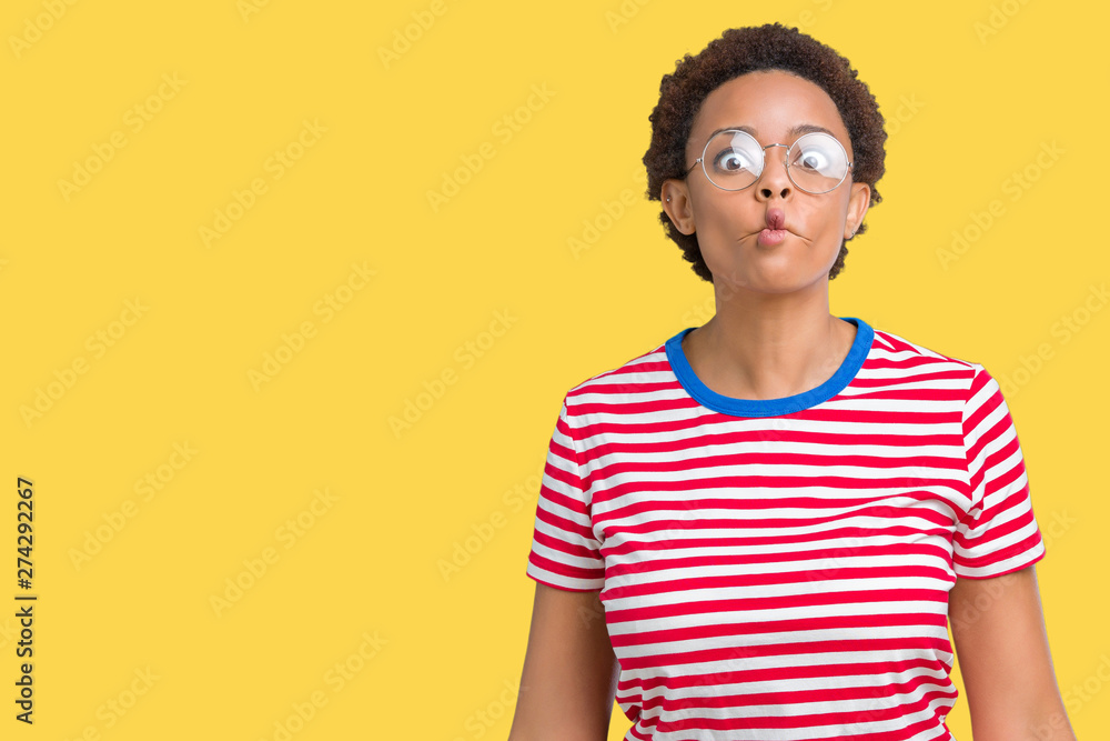 Beautiful young african american woman wearing glasses over isolated background making fish face with lips, crazy and comical gesture. Funny expression. Beautiful young african american woman wearing glasses over isolated background making fish face with lips, crazy and comical gesture. Funny expression.