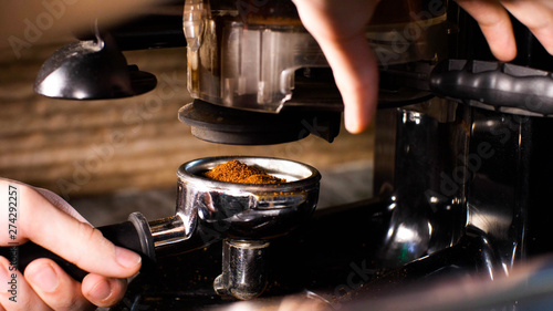 Cuadro en lienzo Barista man is grinding coffee using hand coffee grinder pushing handle, coffee pours into the holder, closeup hands