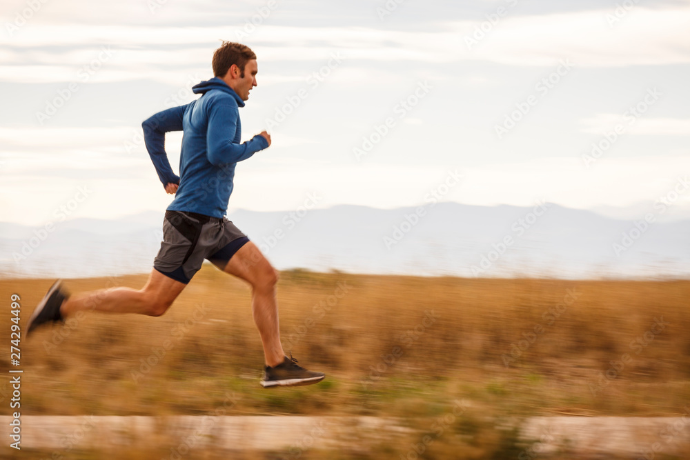 Denver, Colorado, USA: A male runner running along a road in the Rocky Mountain Arsenal NWR whith the Rocky Mointains in the background. Denver, Colorado, USA: A male runner running along a road in the Rocky Mountain Arsenal NWR whith the Rocky Mointains in the background.
