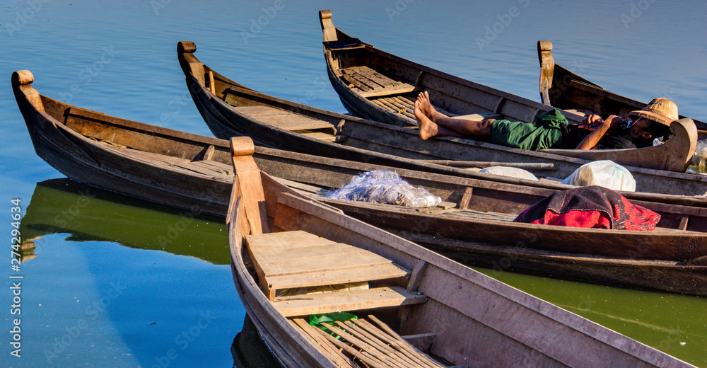 Burmese man taking a nap on wooden fishing boat