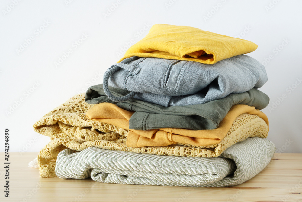 Stack of clothes in yellow green gamma on wooden table Stack of clothes in yellow green gamma on wooden table