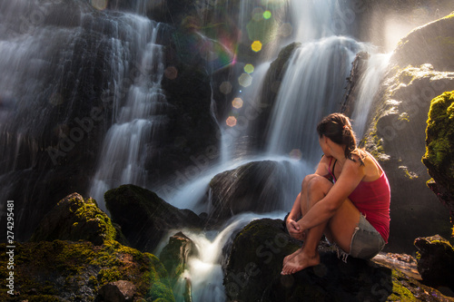 A woman sits by a beautiful Champagne Falls in Hyalite Canyon, Montana in the summer. photo