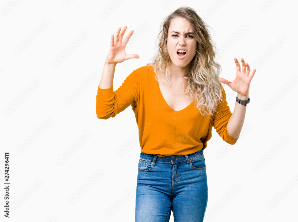 Beautiful young blonde woman over isolated background crazy and mad shouting and yelling with aggressive expression and arms raised. Frustration concept. Beautiful young blonde woman over isolated background crazy and mad shouting and yelling with aggressive expression and arms raised. Frustration concept.