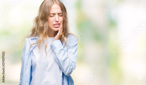 Beautiful young blonde woman over isolated background touching mouth with hand with painful expression because of toothache or dental illness on teeth. Dentist concept.