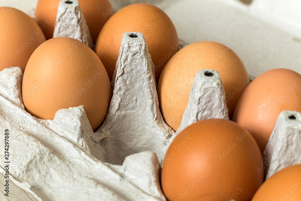 Hen eggs in open cardboard egg carton on kitchen table light copy space background. Healthy organic food and diet concept. Hen eggs in open cardboard egg carton on kitchen table light copy space background. Healthy organic food and diet concept.