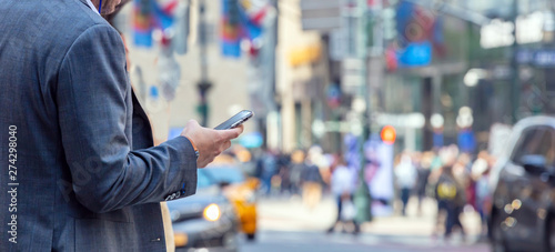 Canvas Print New York, Wall street. Young man in suit holding a smartphone