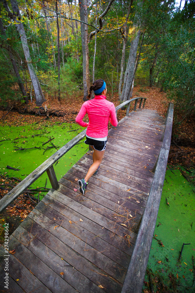 A woman goes for a trail run across an iconic arched wooden bridge along the Center Trail near the main office/trailheads at the Nags Head Woods Preserve. A woman goes for a trail run across an iconic arched wooden bridge along the Center Trail near the main office/trailheads at the Nags Head Woods Preserve.